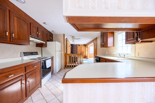 kitchen featuring white appliances, wallpapered walls, light countertops, under cabinet range hood, and a sink