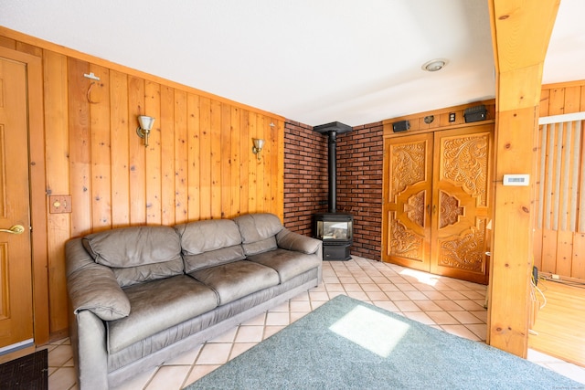 living area with tile patterned floors, a wood stove, and wooden walls