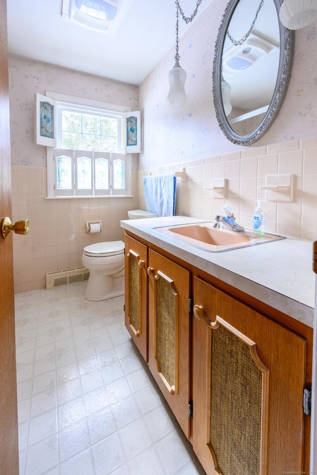 bathroom with wallpapered walls, toilet, wainscoting, vanity, and tile patterned floors