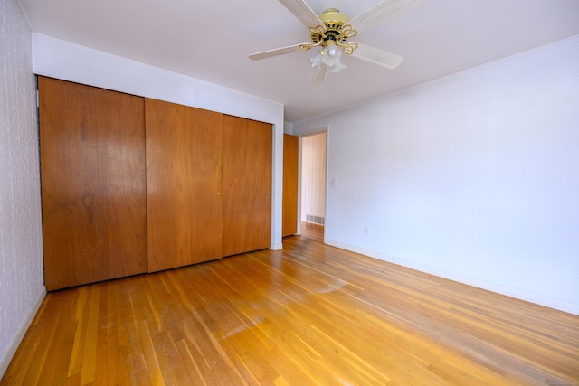 unfurnished bedroom featuring light wood-type flooring, a ceiling fan, baseboards, and a closet