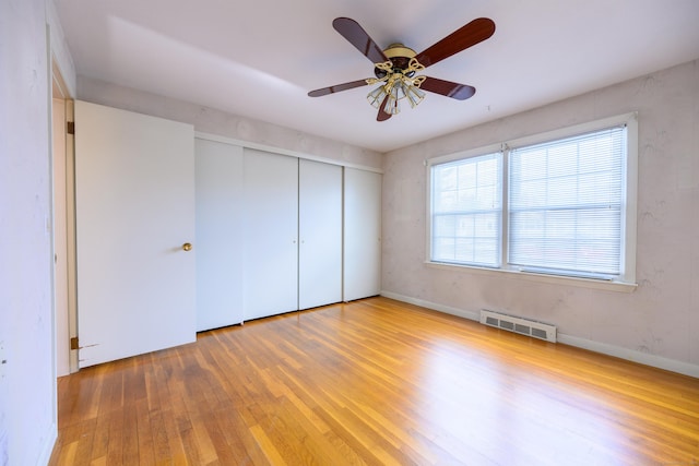 unfurnished bedroom with a closet, wood-type flooring, visible vents, a ceiling fan, and baseboards