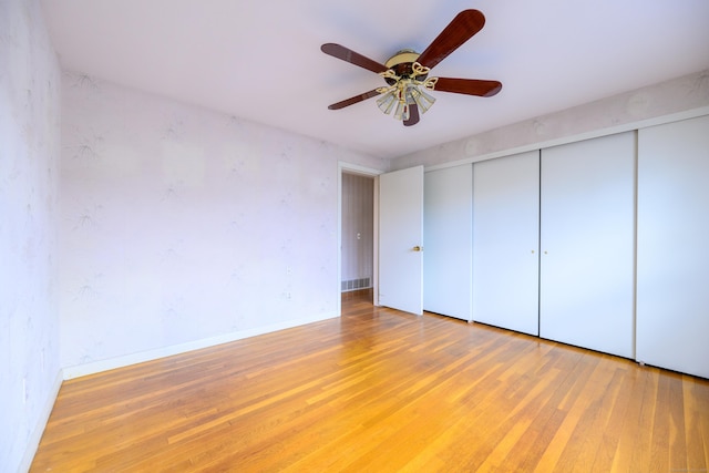 unfurnished bedroom with a closet, ceiling fan, baseboards, and hardwood / wood-style flooring