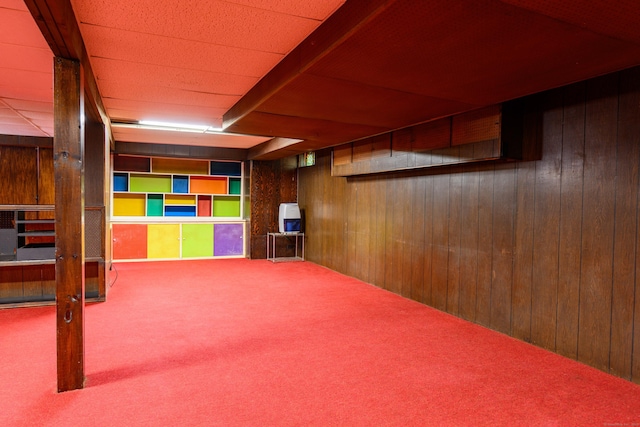 finished below grade area featuring carpet and wooden walls