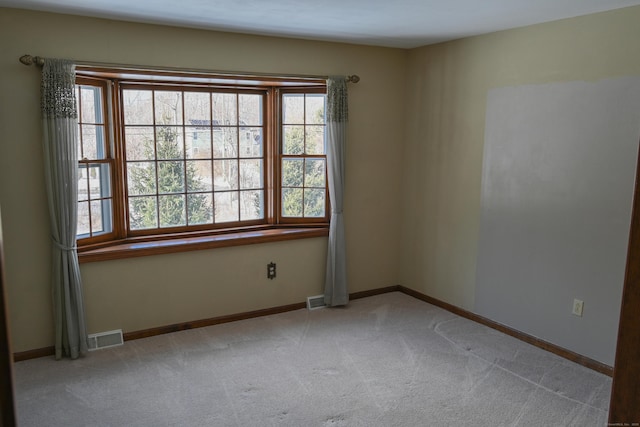 spare room featuring light colored carpet, a healthy amount of sunlight, and visible vents