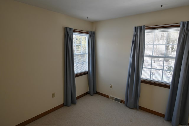 empty room featuring light carpet, baseboards, and visible vents