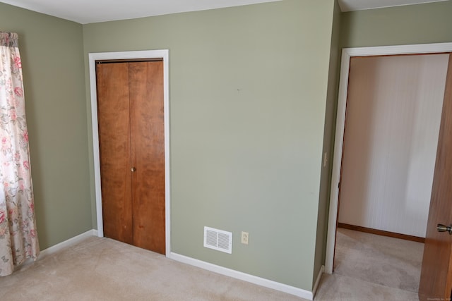 unfurnished bedroom with a closet, visible vents, and light carpet