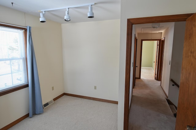 spare room with attic access, light colored carpet, visible vents, and plenty of natural light