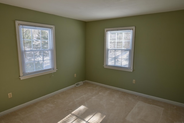 unfurnished room with light colored carpet, visible vents, and baseboards