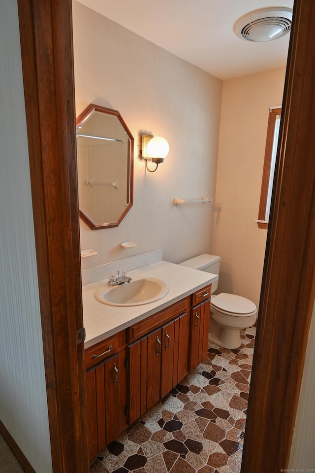 bathroom with toilet, visible vents, walk in shower, and vanity