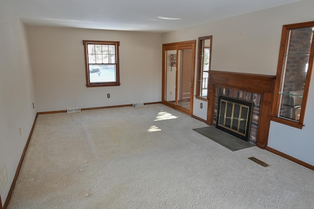 unfurnished living room with light colored carpet, visible vents, a fireplace, and baseboards