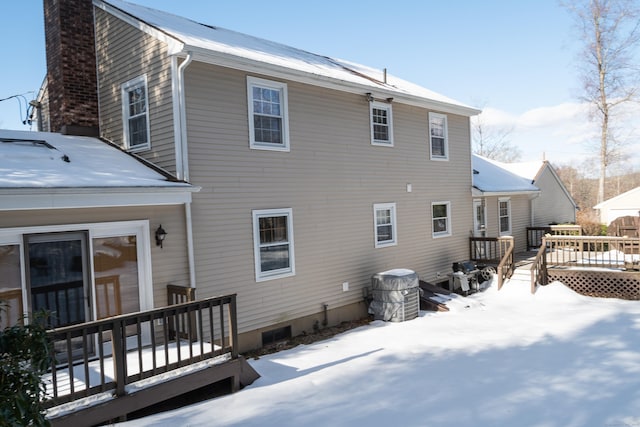 snow covered house featuring a chimney and a deck