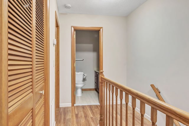 hall featuring light hardwood / wood-style flooring and a textured ceiling