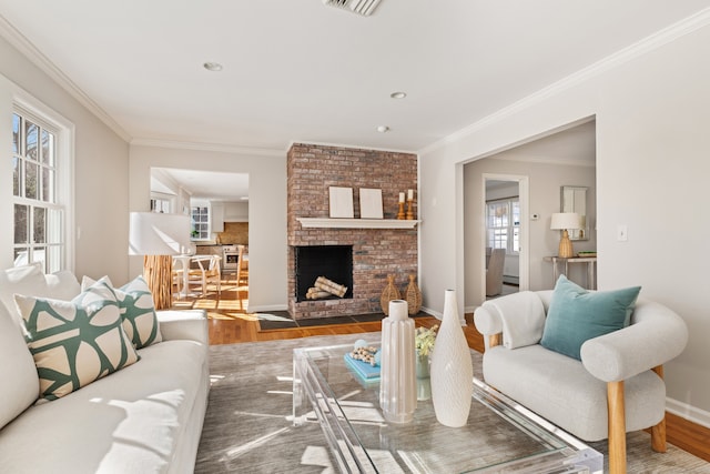 living area featuring ornamental molding, a brick fireplace, baseboards, and wood finished floors