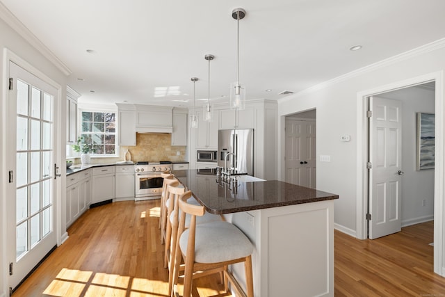 kitchen featuring appliances with stainless steel finishes, white cabinets, decorative light fixtures, and a kitchen island