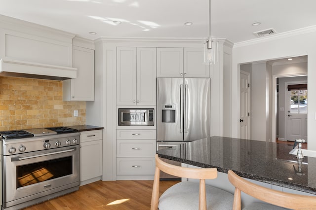 kitchen featuring stainless steel appliances, dark stone countertops, light wood-style flooring, and white cabinets