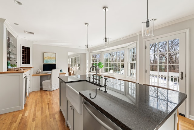 kitchen featuring dishwasher, visible vents, a center island with sink, and pendant lighting