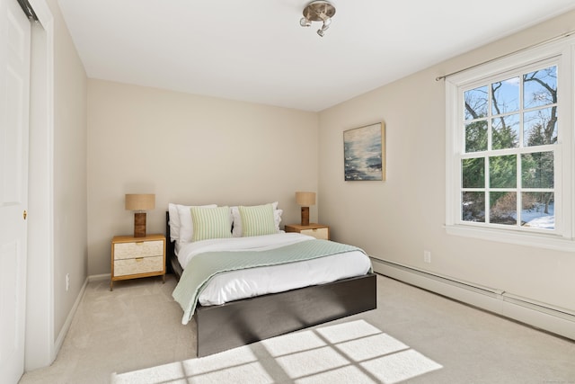 bedroom with a baseboard heating unit, light colored carpet, and baseboards