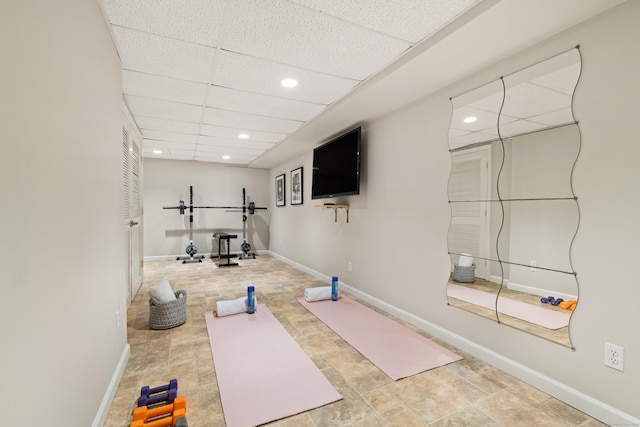 exercise room with recessed lighting, a paneled ceiling, and baseboards