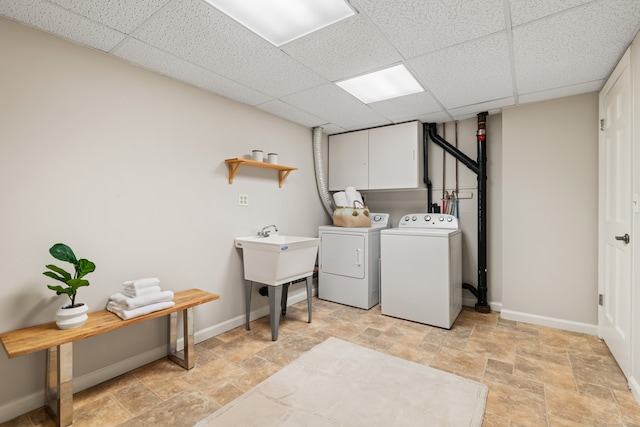 laundry area featuring separate washer and dryer, a sink, baseboards, cabinet space, and stone finish flooring