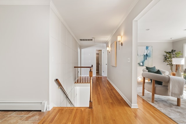 hallway with a baseboard heating unit, wood finished floors, visible vents, an upstairs landing, and crown molding