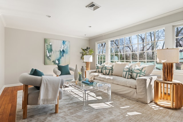 living area featuring ornamental molding, light wood-type flooring, visible vents, and baseboards