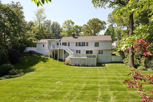 rear view of property with a lawn, a chimney, stairs, fence, and a wooden deck