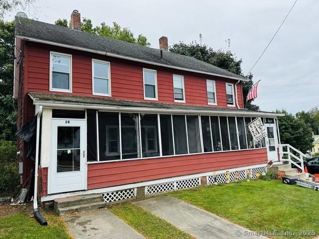 view of front of house featuring entry steps, a front lawn, a chimney, and a sunroom