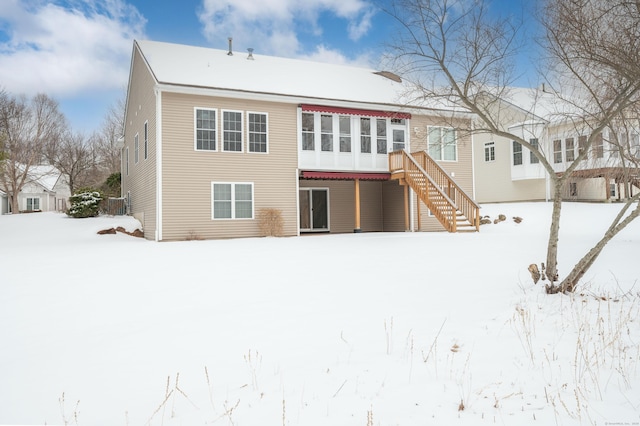 snow covered rear of property featuring stairway