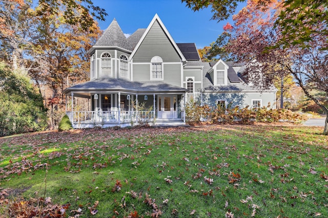 view of front facade featuring covered porch, a front yard, and solar panels