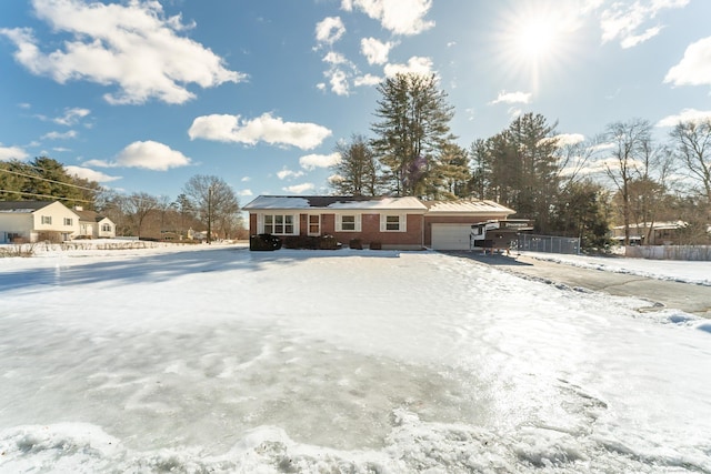 view of front of house with brick siding, an attached garage, and fence