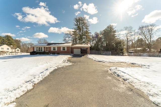 view of front of property with a garage, aphalt driveway, brick siding, and fence