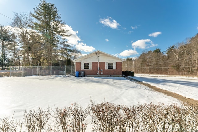 snow covered back of property with fence and brick siding