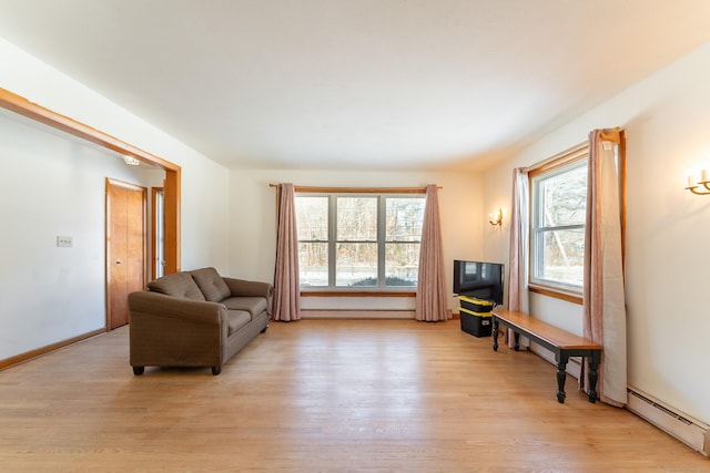 living room featuring a wealth of natural light, a baseboard radiator, baseboards, and light wood finished floors