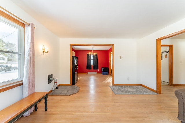 foyer entrance featuring a notable chandelier, baseboards, and light wood finished floors