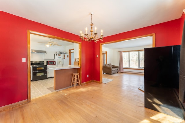 kitchen featuring double oven range, light wood-type flooring, extractor fan, white refrigerator with ice dispenser, and open floor plan