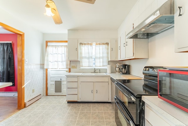 kitchen with baseboard heating, double oven range, under cabinet range hood, and a sink