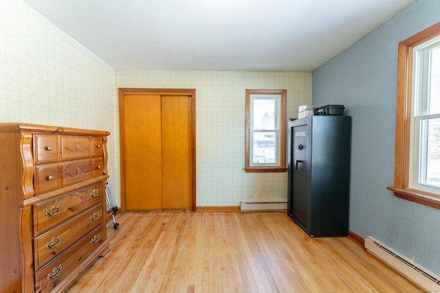 bedroom with a baseboard radiator, light wood finished floors, baseboards, and wallpapered walls