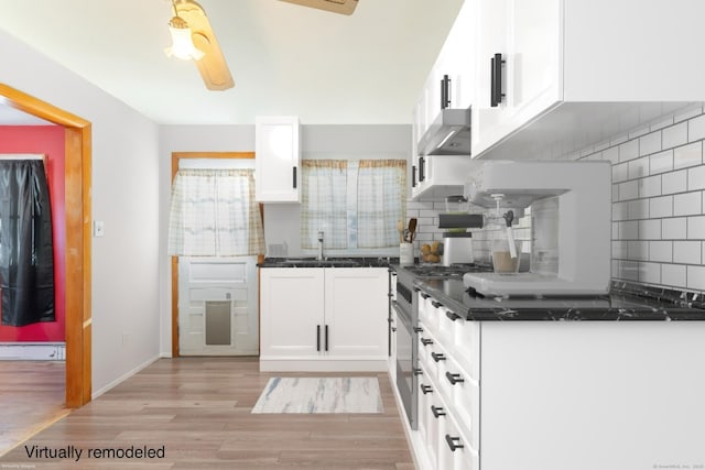 kitchen featuring high end range, light wood finished floors, a baseboard radiator, white cabinetry, and tasteful backsplash