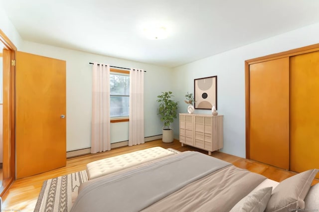 bedroom with light wood-type flooring and baseboard heating