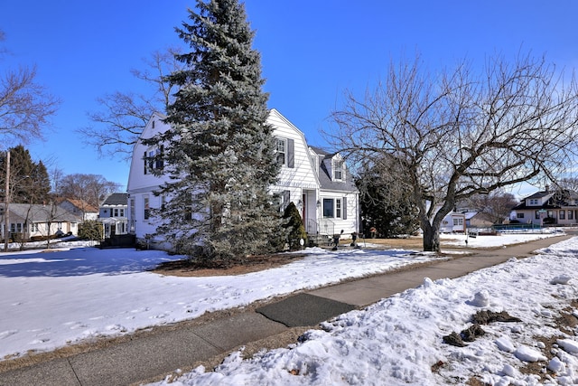 view of snow covered exterior featuring a residential view and a gambrel roof