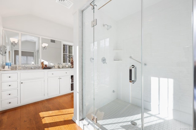 full bathroom with a stall shower, visible vents, wood finished floors, and vanity