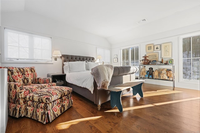 bedroom with lofted ceiling, multiple windows, and wood finished floors