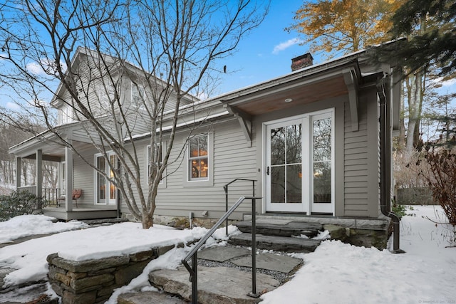 snow covered rear of property featuring a chimney