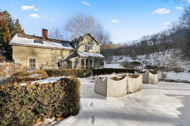 view of snowy exterior featuring a chimney