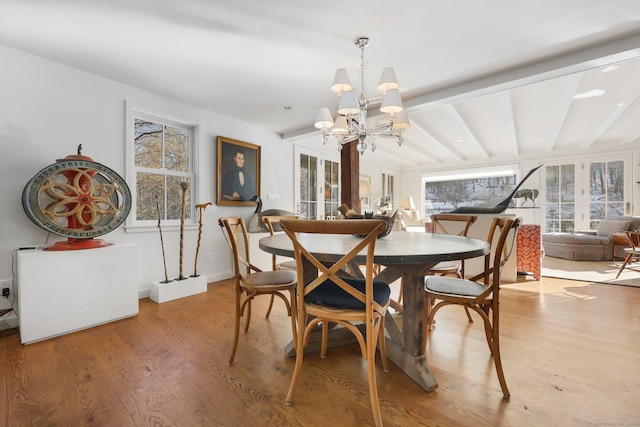 dining area featuring a notable chandelier, light wood-style flooring, and lofted ceiling with beams