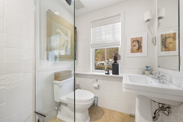 bathroom with toilet, visible vents, and tile walls