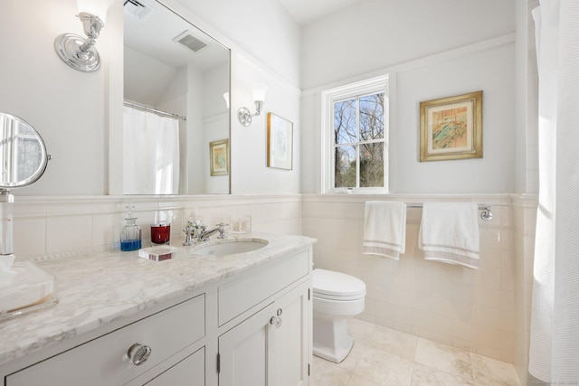 bathroom with toilet, visible vents, tile walls, and vanity