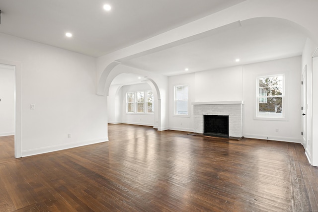 unfurnished living room featuring baseboards, a brick fireplace, wood finished floors, and recessed lighting