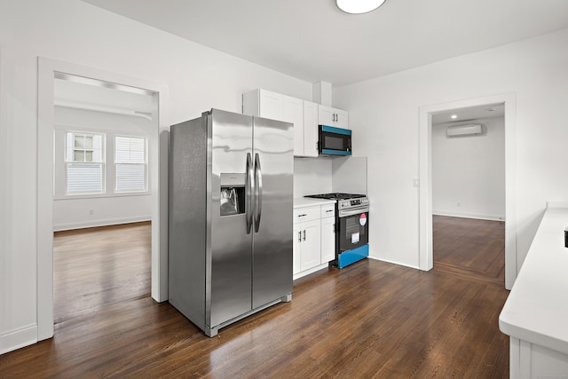 kitchen with stainless steel appliances, white cabinets, an AC wall unit, light countertops, and dark wood finished floors