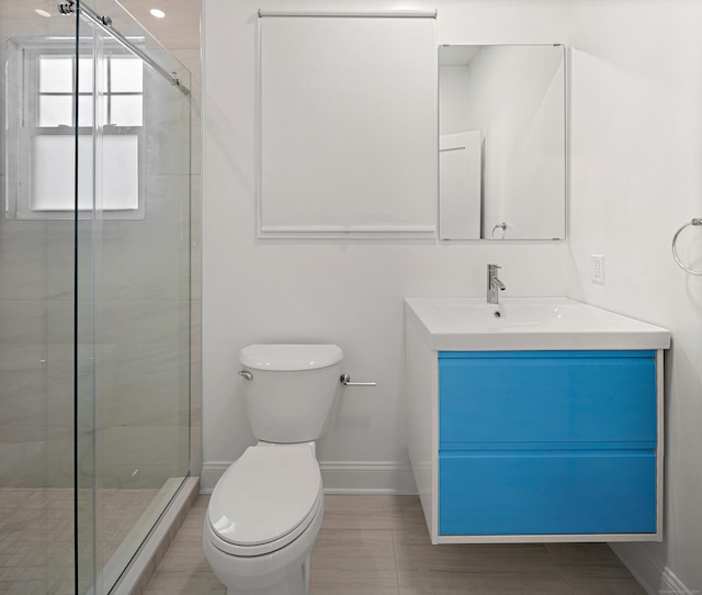 full bath featuring a stall shower, vanity, toilet, and baseboards